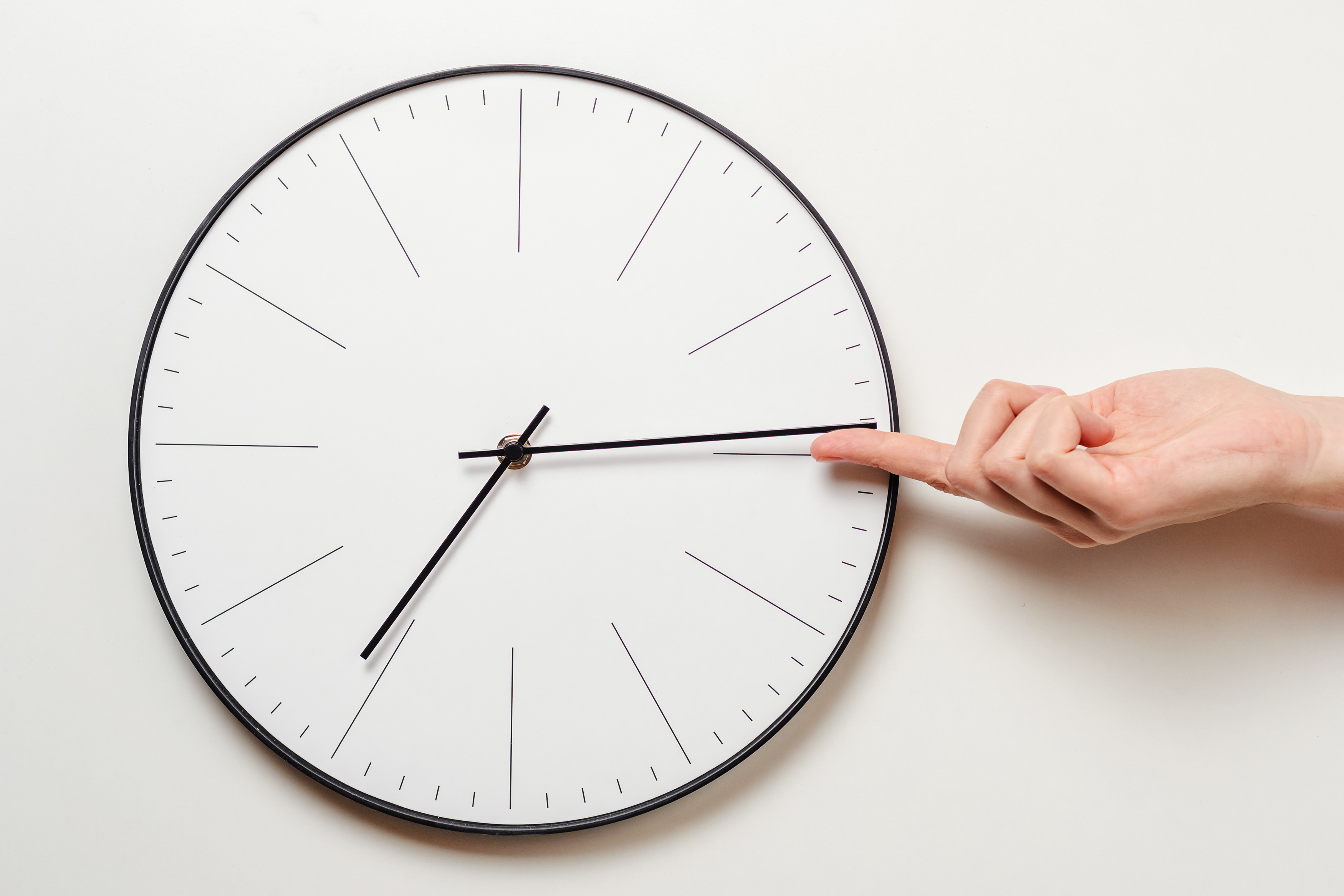 Frauenhand stoppt Zeiger in einer Uhr